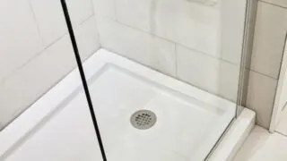 Applying spray foam under a shower pan to reduce flex.